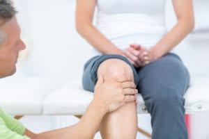 Male doctor assessing knee pain