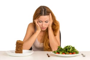 young woman deciding between healthy and unhealthy foods