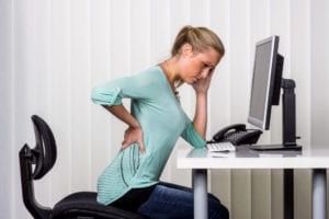 woman sitting at desk with back injury